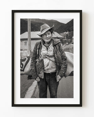 Tibetan man in a broad-brimmed hat and layered jacket in a black and white northern China portrait.