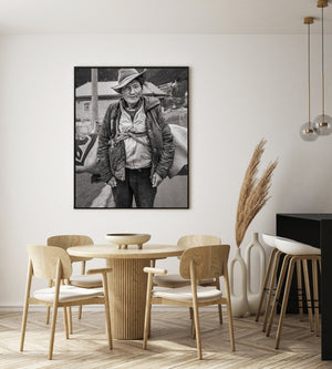 Direct portrait of a Tibetan man wearing a creased brimmed hat and padded jacket.