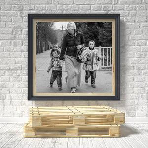 Black and white family street photograph in Qinghai with trees and a white railing.