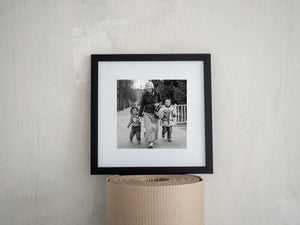 A woman and two children approach the camera in a monochrome documentary photograph.