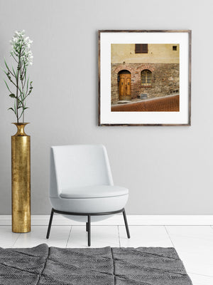 Rustic Tuscan doorway beneath an ochre plaster wall and closed shutters.
