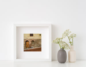 Weathered masonry and a brick-paved lane outside a traditional Tuscan home.