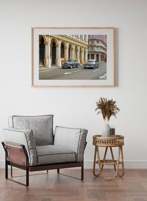 Vintage cars and tall columns create a colourful Cuban street scene.