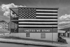 Large painted stars and stripes cover a building wall above the words United We Stand.