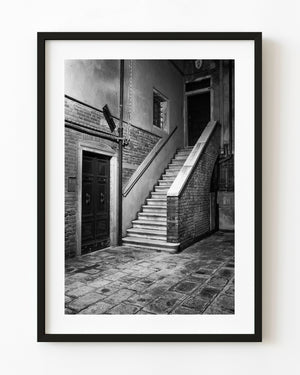 Steintreppen und dunkle Holztüren in einem Innenhof in Venedig in Schwarz und Weiß
