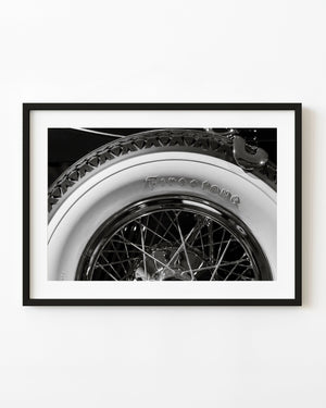 Vintage wire wheel and Firestone whitewall tyre in black and white.
