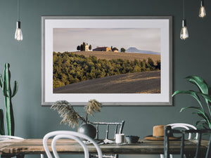 Rolling farmland beneath a chapel and farmhouse in Tuscany.