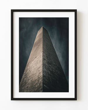 Washington Monument viewed from below against a dark textured sky.