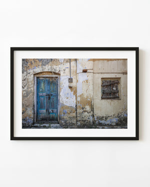 Weathered blue door and boarded window on a peeling wall in Ooty