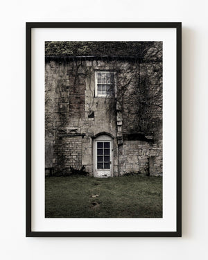 Weathered English country home with a white door and bare climbing vines