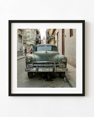 Weathered green classic car parked on a narrow Havana street