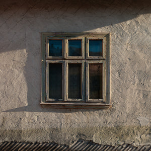 Old wooden farmhouse window set in cracked Romanian plaster