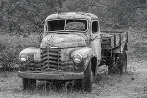 Old flatbed truck with worn paint and a cracked windshield