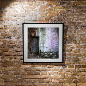 Colour photograph of a weathered wooden door and distressed brick wall