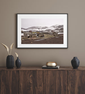 Abandoned timber building and rusted tanks in an Antarctic landscape