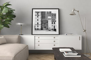 Black and white city photograph of weathered warehouses and an overhead passage