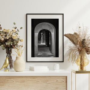 Layered arches framing a woman beside a dark wooden doorway