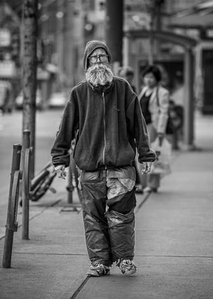 Toronto street portrait of a bearded man against softly blurred pedestrians and shopfronts.