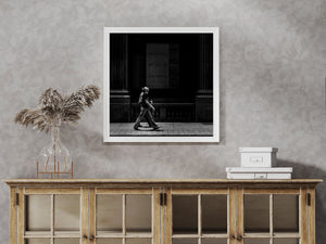 A pedestrian crosses a strip of light below plywood-covered windows and heavy Toronto columns.