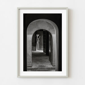 Vietnamese woman in conical hat framed by arched doorway in black and white