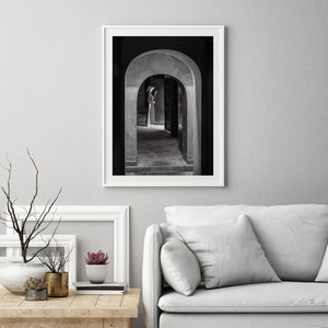 Schwarz-Weiß-Fotografie einer Frau, die in geschichteten Architekturbögen steht