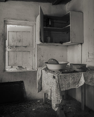 Monochrome photograph of a deserted Bahamas kitchen with bowls, a pot and worn walls.