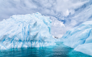 Blassblaue Mulden und scharfe Eiskämme umrahmen einen antarktischen Wasserkanal.