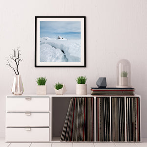 A deep opening in Antarctic snow leading toward a small exposed summit.