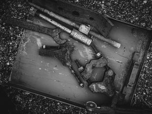 Overhead black and white view of worn industrial tools gathered in a shallow tray.