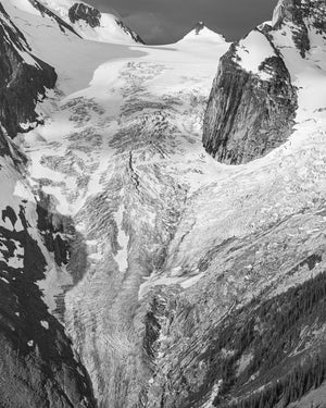 Pale glacier ridges descend beneath steep rocky cliffs in a Canadian alpine landscape.