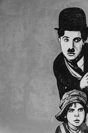 A painted Charlie Chaplin figure appears above a boy against a worn wall in Cuba.