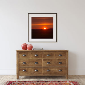 Colour Quebec landscape photograph of a glowing sun above shadowed fields and a low horizon.