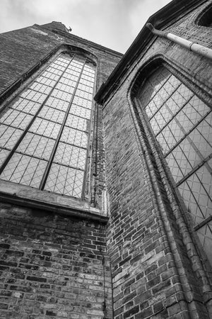 Ein Blick nach oben zeigt spitze Kirchenfenster und strukturierte historische Backsteinwände.