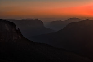 Layered Blue Mountains ridges fade into haze beneath a warm sunrise sky