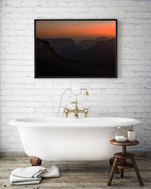 Dark sandstone cliffs frame a deep valley under soft orange dawn light