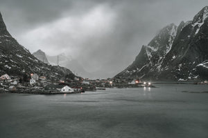 Stimmungsvolle Aussicht auf das Dorf Reine neben ruhigem Wasser in Norwegen