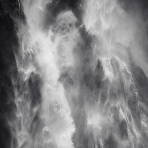 Niebla blanca y agua que cae cruzando una pared de roca oscura