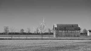 Grange en bois patiné sous des éoliennes lointaines