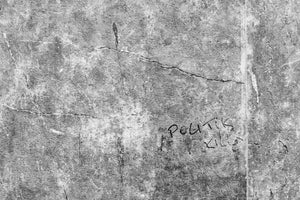 Handschriftliche Botschaft „Politics Kills“ unter Rissen in einer rauen Betonwand