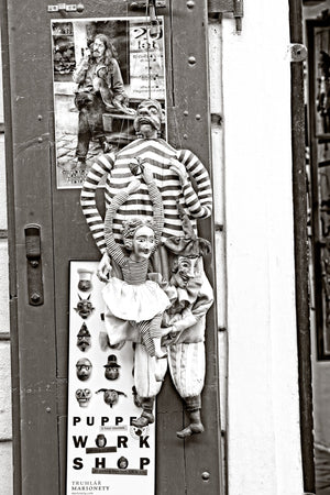 Striped marionettes and a jester displayed against a Prague shop door