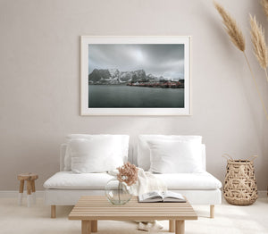 Snow-streaked mountains rising behind red and white coastal buildings