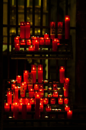 Rangées de bougies de prière rouges brillant contre un intérieur sombre d'église