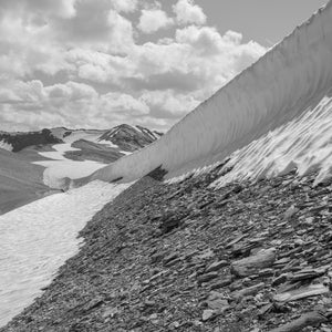 Tall curved snowbank above a rocky alpine slope