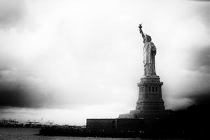 Moody New York harbor view with Liberty rising from a shadowed pedestal.