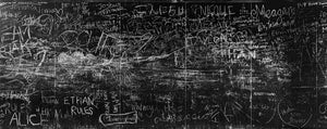 Sydney-Tafelwand, bedeckt mit überlappenden weißen Graffiti und handgezeichneten Markierungen.