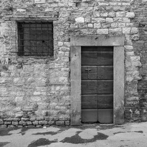 Puerta de madera antigua y mampostería de piedra tosca en la fachada de un pueblo toscano.