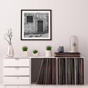 Fotografía arquitectónica en blanco y negro de una cruz fijada a una puerta de madera envejecida.