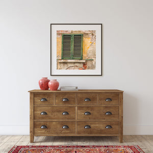 Faded green louvres surrounded by worn ochre plaster