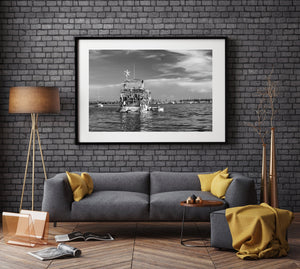 Black and white stern view of a weathered boat among anchored sailboats