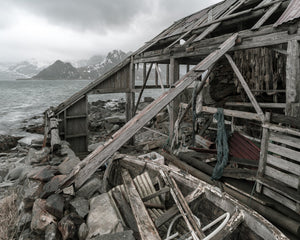 Collapsed timber boathouse with fishing nets and a wooden boat in Lofoten